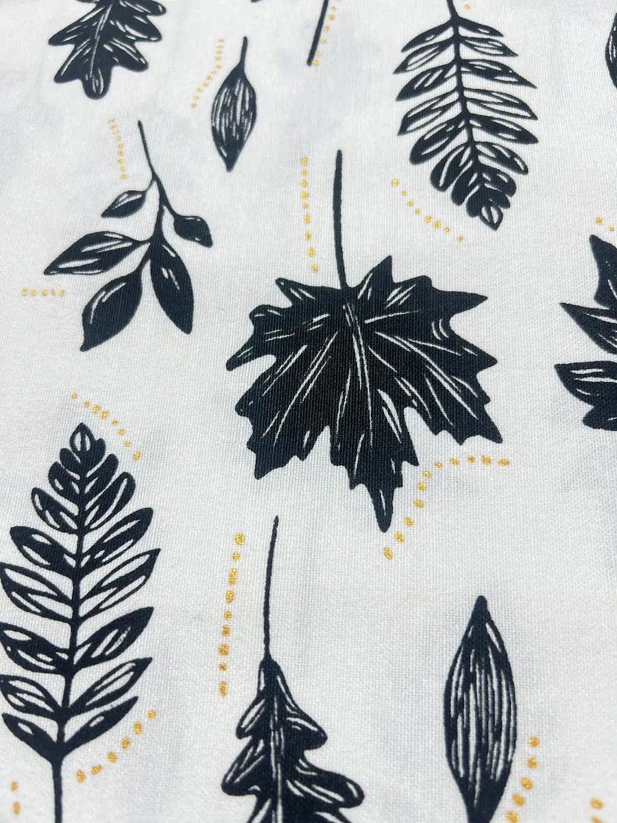 White fabric with a repeating pattern of black botanical leaf silhouettes and small dotted yellow lines.
