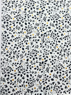 White fabric or paper featuring a dense black botanical pattern of leaves, stems, and small scattered gold dots.
