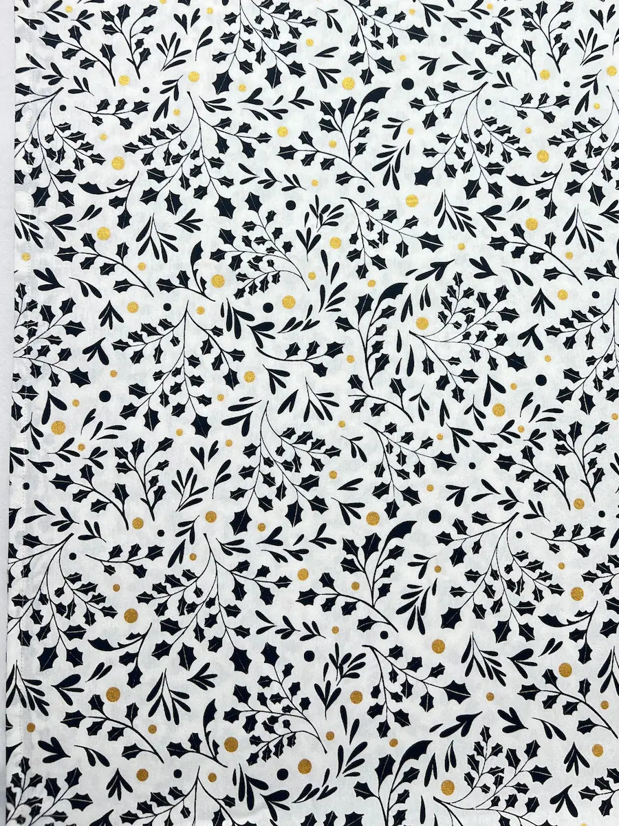 White fabric or paper featuring a dense black botanical pattern of leaves, stems, and small scattered gold dots.
